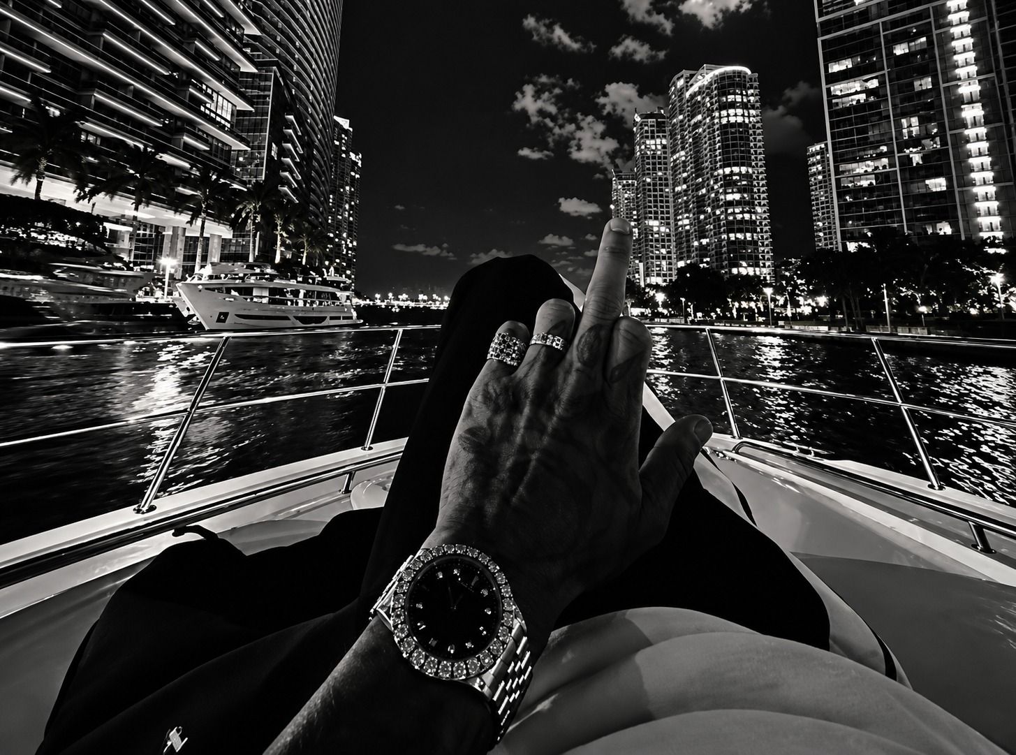 Hand with a diamond watch and rings on a yacht at night beside city towers